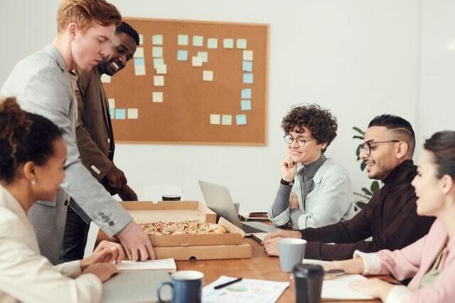 a group of people sitting around a table with a projector screen