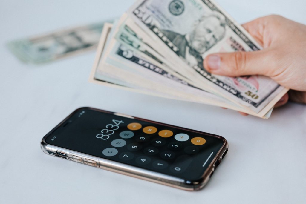 a hand holding a calculator and a stack of cash