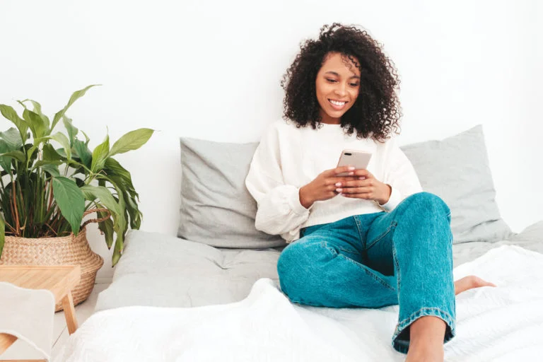 a person sitting on a bed holding a phone